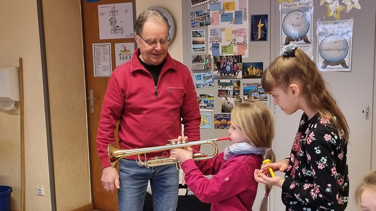 Unter Anleitung eines Musikers versuchen sich die Kinder im Trompetespielen